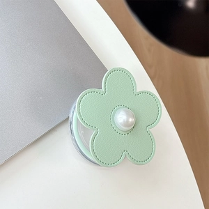 Detail of light green leather flower phone socket with center pearl on white desk