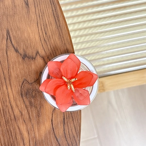 Vue macro d'une fleur rouge en résine à 5 pétales avec étamines dorées sur bois
