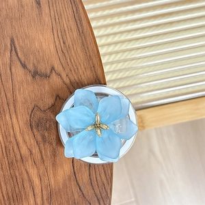 Détail du support téléphone fleur bleu clair avec centre doré sur bois de noyer
