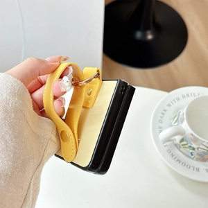 Detailed view of yellow lychee leather case with wrist strap and floral metal charm