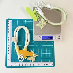 Nahaufnahme der handgewebten Handyschlaufe mit Schmetterlingsanhänger und 24g Gewicht