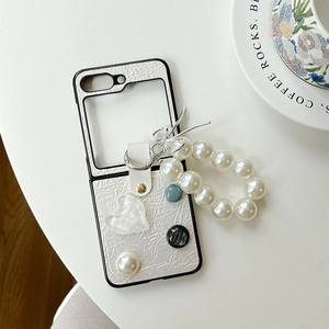 Détail de l'étui en cuir blanc perle pour Z Flip avec chaîne en perles et cœurs