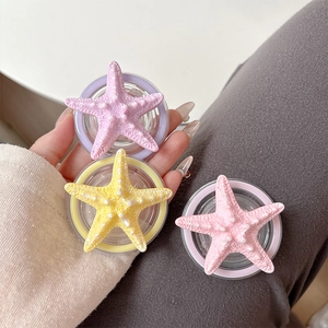 Realistic starfish phone grip holders in purple, yellow, and pink with textured finish