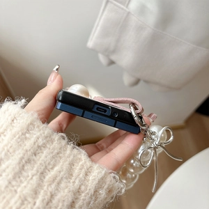 Gros plan d'une coque bicolore avec dragonne en cuir rose et breloque papillon perle