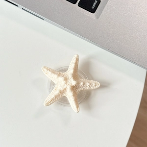 Close-up of cream starfish phone grip with realistic textured details on white desk