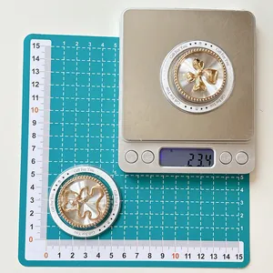Close-up of golden bear and butterfly charms on a scale showing 23.4g and 5cm diameter