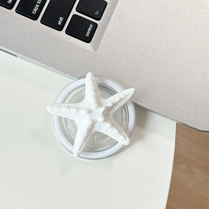 Detail of 3D white starfish phone grip holder showing realistic resin texture on a desk