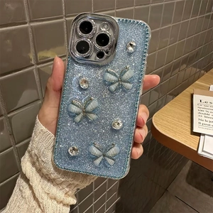 Light blue glitter iPhone case with rhinestones and 3D bows held in a cozy home setting