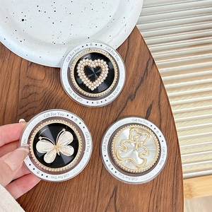 Detail of floral pearl bow and heart magnetic phone grips with metallic finish on a desk