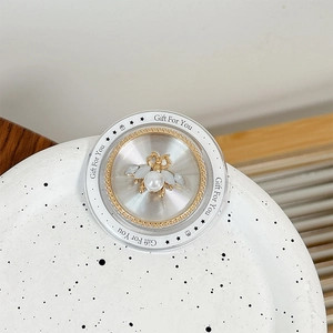 Detail of floral bee phone grip with pearl inlay on a decorative ceramic tray