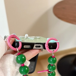 Dettaglio custodia in pelle verde con libellula argento e cordino di perle colorate