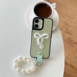 Detail of leather phone case featuring a large pearl bow and elegant beaded wrist strap