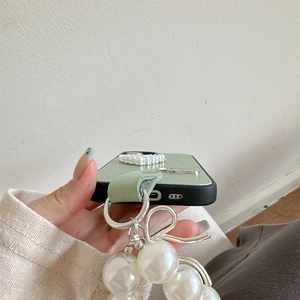 Dettaglio di porta ricarica e altoparlante su custodia in pelle verde chiaro con cuore