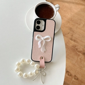 Close-up of pink wrinkled leather phone case with pearl chain and bow detail