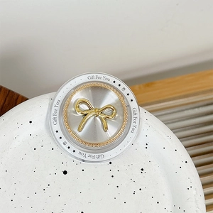 Macro view of a golden bow phone grip with Gift For You text on a ceramic plate