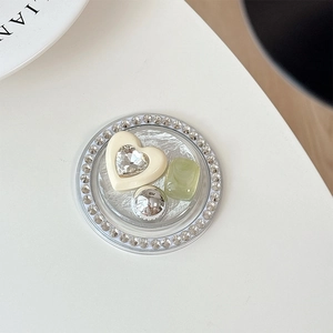 Close-up of a circular phone grip with faux pearls, rhinestones and heart gemstone
