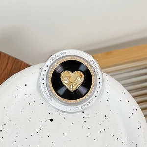 Detail of magnetic phone grip featuring golden heart on black record base in clear acrylic