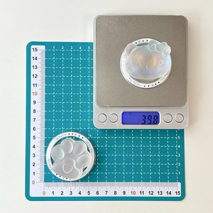Macro shot of Hello Kitty and cat paw resin accessories on a digital scale for size check