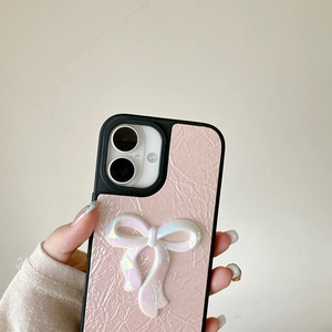 Pink faux leather iPhone case featuring a large 3D iridescent pearl bow and chain detail