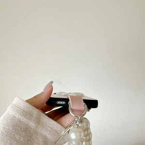 Detail of pink leather phone case with large white faux pearl chain strap accessory