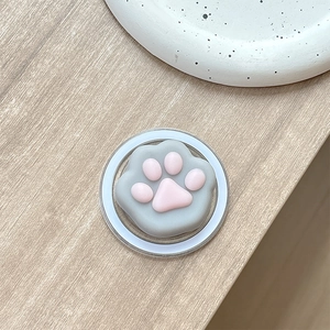 Close-up of 3D cat paw pop socket phone holder in pink and grey on wooden surface
