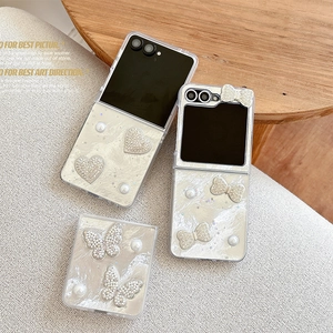 Pearlescent white Samsung Z Flip 6 case with elegant pearl hearts and crystal bows
