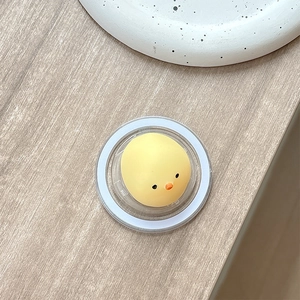 Top-down view of a cute yellow chick squishy grip toy on a rustic wooden desk