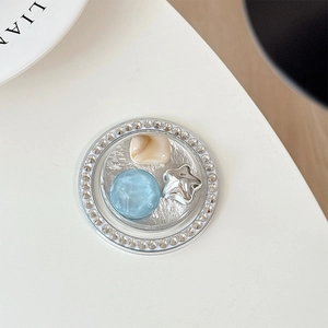 Detailed macro of a rhinestone phone grip featuring a cream bead and a silver star charm