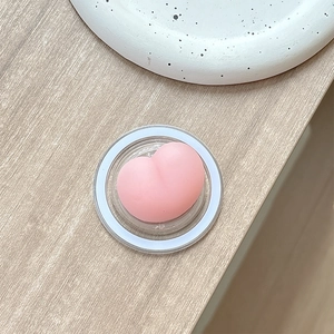 Close-up of a soft pink heart-shaped squishy phone grip on a clear acrylic base