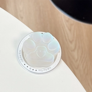 Detail of a pearlescent white cat paw phone grip with a heart-shaped pad on a round base
