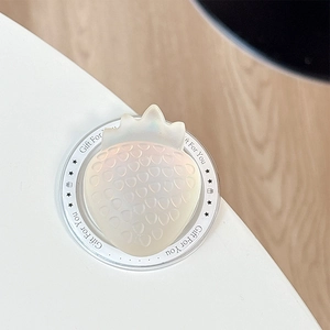 Detail of strawberry-shaped phone grip with iridescent pearl finish on a white surface