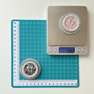 Macro detail of round pearl phone grip with bowknot showing 5.5cm diameter and 28.8g weight
