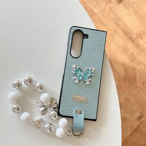 Detail of grey-green crinkled leather phone case with rhinestone butterfly and beaded lanyard