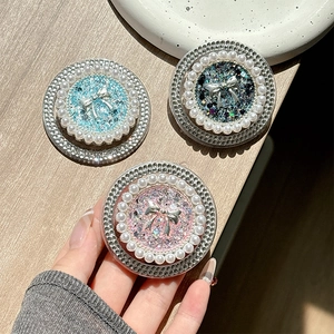 Macro detail of round phone grip with pearl bow design and sparkling rhinestone border