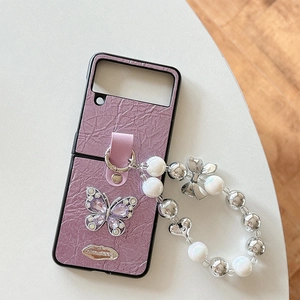 Macro view of purple pleated phone case with rhinestone butterfly and beaded charm strap