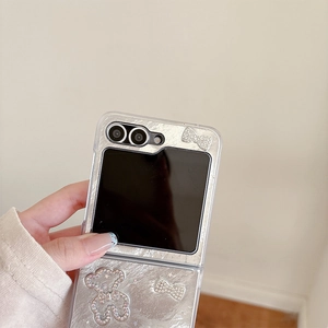 Detailed view of silver flip phone case featuring rhinestone bear and bow decoration