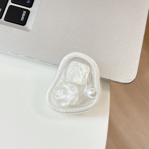 White flower cell phone grip with pearls and sequins shown next to a laptop