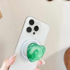 Nahaufnahme der grünen Herz-Handyhalterung mit Jade-Muster auf einem weißen Smartphone