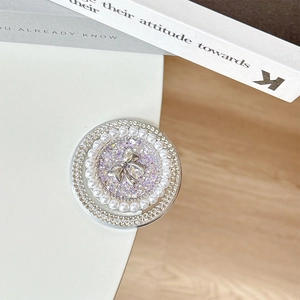Macro detail of round phone grip featuring silver bow, purple sequins and pearls