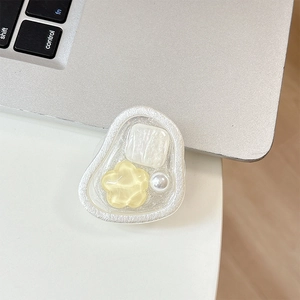 Detail of cream flower beaded magnetic phone grip holder on laptop keyboard