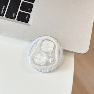 Detail of white floral grip tok with pearl bezel on a silver laptop background