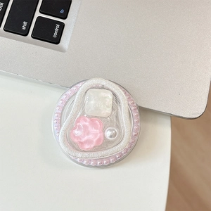 Top view of a round floral grip tok with pink pearls and resin flower on a laptop desk