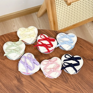 Colorful bow hair accessory set on heart cards across a natural wooden table