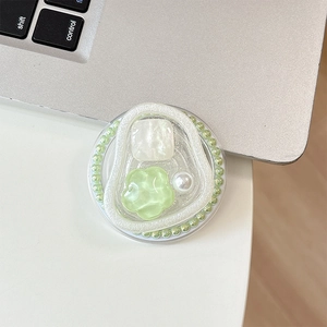 Macro view of a round beaded phone grip featuring a light green flower and pearls
