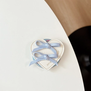 Close-up of heart-shaped faux leather phone socket with light blue ribbon bows and stitching