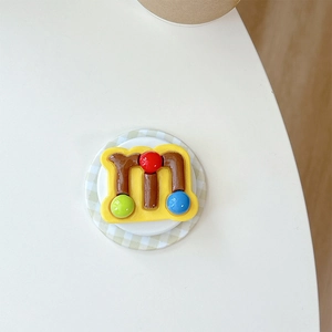 Macro shot of 3D yellow phone socket with a brown letter M and colorful bead accents
