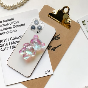 Close-up of 3D bear phone grip with iridescent laser glitter on white smartphone