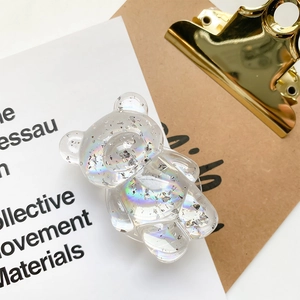 Close-up of iridescent resin bear phone grip with silver foil flakes on white surface