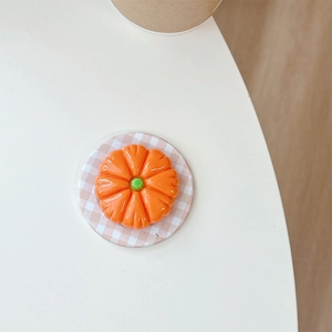 Macro view of a 3D pumpkin phone grip with glossy finish on a minimalist coaster