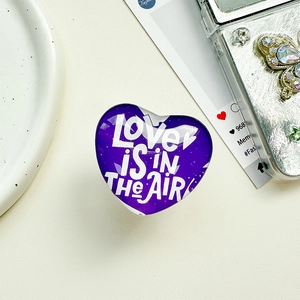 Detailaufnahme der herzförmigen Handyhalterung mit Love is in the air Aufdruck